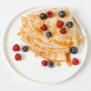 A plate of pancakes with berries and syrup