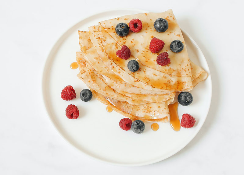 A plate of pancakes with berries and syrup